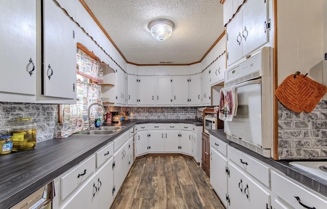 5011 Sunny Acres Dr, Waynesboro, TN 38485 - kitchen featuring a textured ceiling, dark countertops, backsplash, white oven, and dark wood finished floors