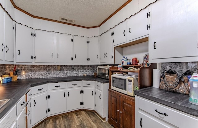 5011 Sunny Acres Dr, Waynesboro, TN 38485 - kitchen with dark countertops, a textured ceiling, white microwave, tasteful backsplash, and white cabinets