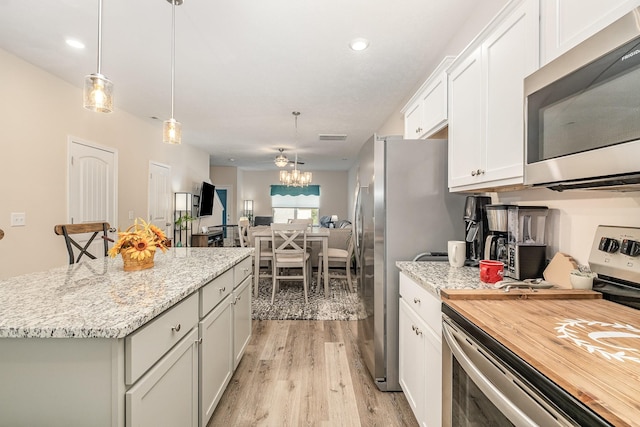 523 Moshe Flam Pl, La Vergne, TN 37086 - kitchen featuring stainless steel appliances, light wood-style floors, open floor plan, white cabinetry, and a center island