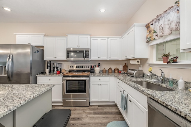 523 Moshe Flam Pl, La Vergne, TN 37086 - kitchen with appliances with stainless steel finishes, light wood-style floors, white cabinetry, recessed lighting, and light stone counters