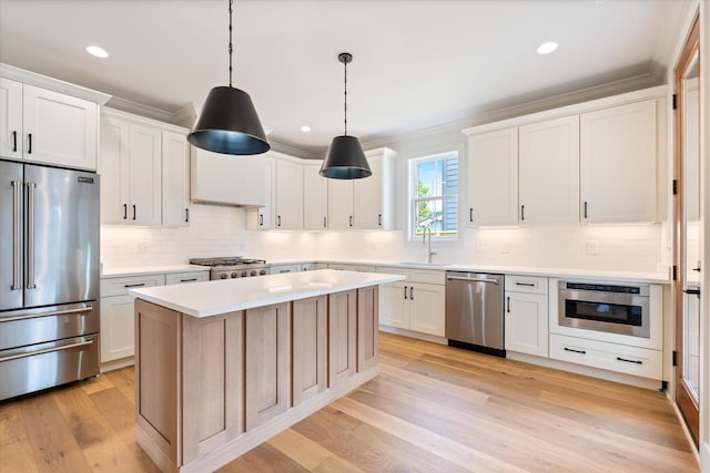 1135 Delmas Ave, Nashville, TN 37216 - kitchen featuring appliances with stainless steel finishes, decorative backsplash, light countertops, a center island, and light wood-type flooring