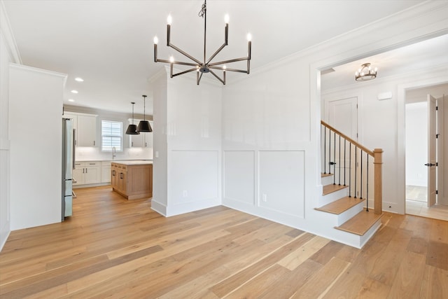 1135 Delmas Ave, Nashville, TN 37216 - unfurnished dining area featuring a chandelier, a decorative wall, light wood-type flooring, ornamental molding, and stairs