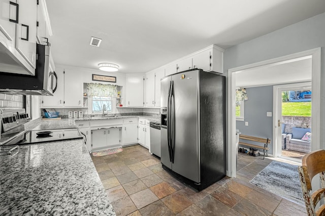 1036 Locke Creek Rd, Readyville, TN 37149 - kitchen with stainless steel appliances, stone tile floors, healthy amount of natural light, and white cabinetry