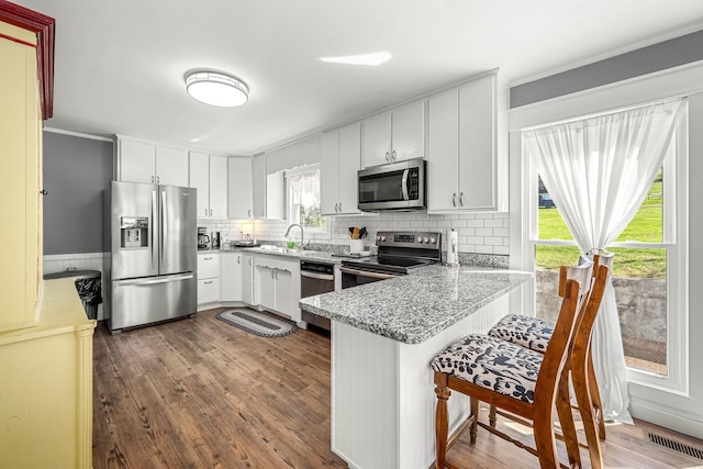1036 Locke Creek Rd, Readyville, TN 37149 - kitchen with stainless steel appliances, a peninsula, dark wood-style flooring, backsplash, and a kitchen breakfast bar