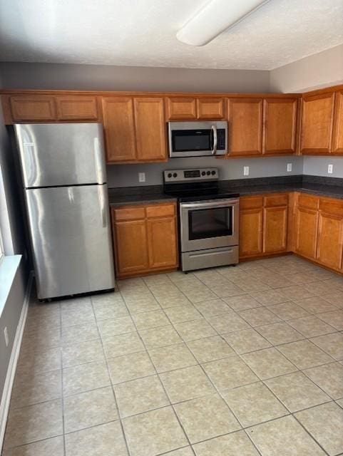 348 Arapaho Dr, Murfreesboro, TN 37128 - kitchen featuring appliances with stainless steel finishes, light tile patterned flooring, brown cabinetry, and dark countertops