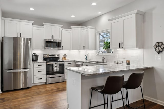 2016 Roderick Cir, Franklin, TN 37064 - kitchen with appliances with stainless steel finishes, a peninsula, white cabinets, light stone counters, and recessed lighting