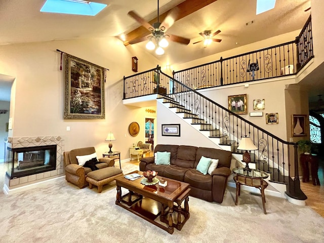 2214 Henpeck Ln, Franklin, TN 37064 - carpeted living room featuring high vaulted ceiling, stairs, ceiling fan, a tile fireplace, and a skylight