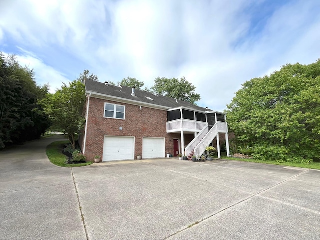 2214 Henpeck Ln, Franklin, TN 37064 - rear view of property featuring a sunroom, brick siding, stairs, driveway, and a garage