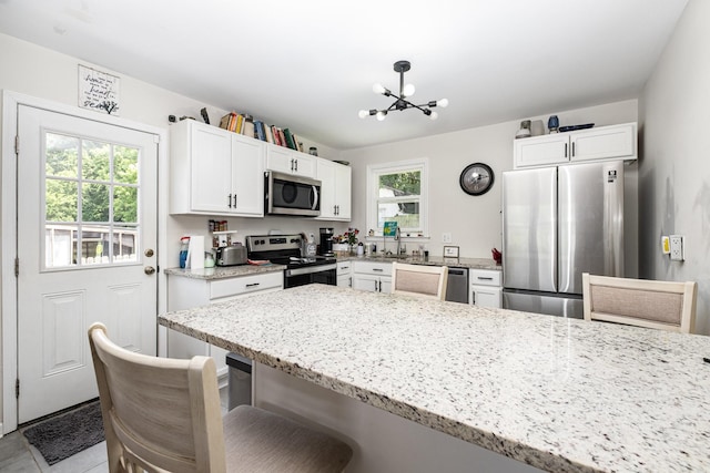 100 Beech St, Columbia, TN 38401 - kitchen featuring stainless steel appliances, a kitchen bar, white cabinets, a chandelier, and light stone countertops