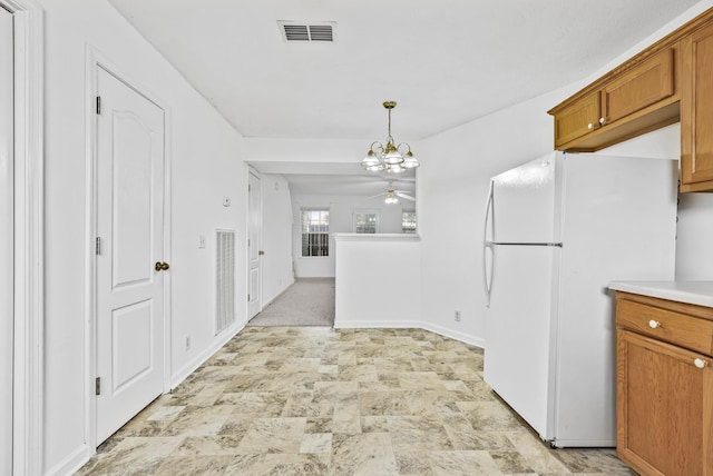 912 Patty Cv, La Vergne, TN 37086 - kitchen with freestanding refrigerator, stone finish floors, brown cabinets, ceiling fan, and a chandelier