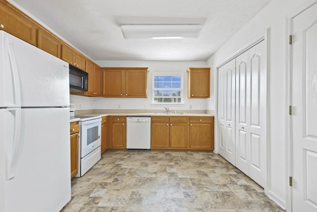 912 Patty Cv, La Vergne, TN 37086 - kitchen with white appliances, light countertops, stone finish floors, and brown cabinets