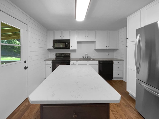 7120 Sutton Pl, Fairview, TN 37062 - kitchen with black appliances, wood finished floors, a center island, and white cabinetry