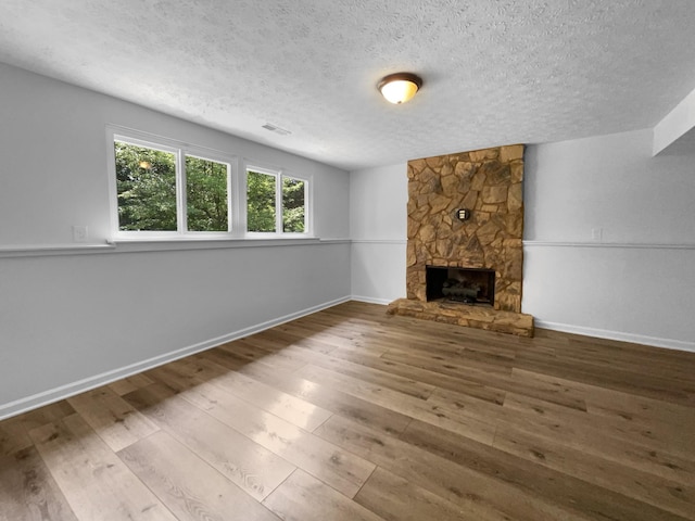 7120 Sutton Pl, Fairview, TN 37062 - unfurnished living room featuring a textured ceiling, hardwood / wood-style flooring, and a stone fireplace