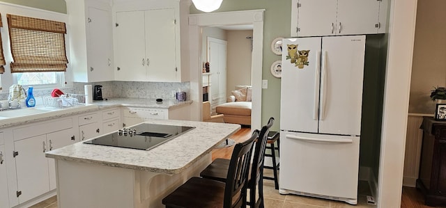 315 Seven Mile Ferry Rd, Cunningham, TN 37052 - kitchen with freestanding refrigerator, black electric stovetop, white cabinetry, a kitchen island, and decorative backsplash