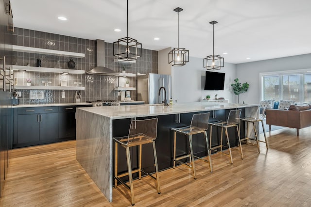 705 27th Ave N, Nashville, TN 37208 - kitchen featuring wall chimney range hood, freestanding refrigerator, backsplash, open floor plan, and a large island with sink