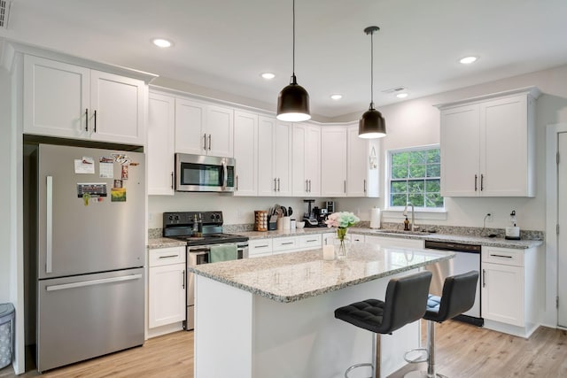 94 Hickory Ridge Ln, Woodbury, TN 37190 - kitchen with stainless steel appliances, white cabinetry, light wood finished floors, a center island, and a kitchen bar