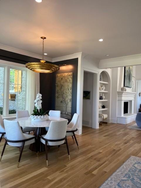119 Winslow Rd, Franklin, TN 37064 - dining area featuring a fireplace with raised hearth, light wood-type flooring, built in shelves, recessed lighting, and ornamental molding