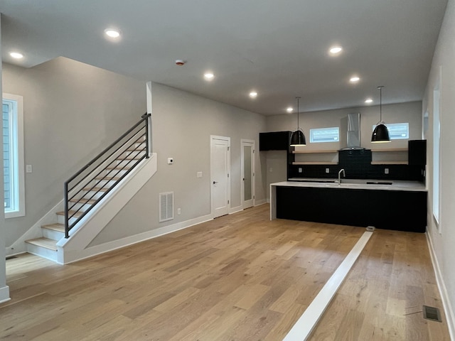 1206 1st Ave Unit 4, Nashville, TN 37210 - kitchen with wall chimney range hood, dark cabinets, light countertops, light wood-style flooring, and decorative light fixtures