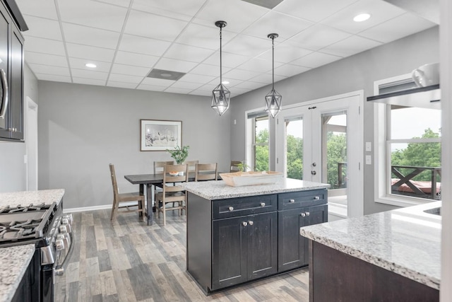 1250 Ed Seay Gregory Ln, Hartsville, TN 37074 - kitchen featuring light wood-type flooring, gas range, a center island, decorative light fixtures, and light stone countertops