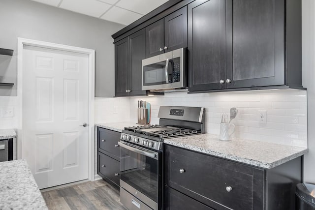 1250 Ed Seay Gregory Ln, Hartsville, TN 37074 - kitchen with appliances with stainless steel finishes, light wood-style flooring, tasteful backsplash, and dark cabinetry