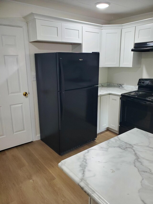 1171 5th St, Jellico, TN 37762 - kitchen with black appliances, ventilation hood, white cabinets, light stone counters, and light wood-style flooring