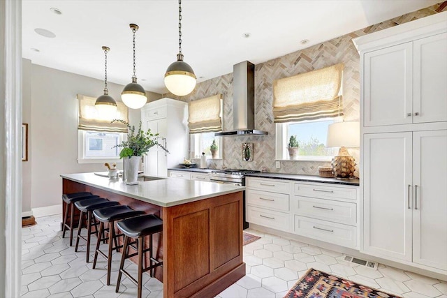 709 S Greenwood Ave S, Chattanooga, TN 37404 - kitchen with wall chimney range hood, a breakfast bar area, a center island, hanging light fixtures, and tasteful backsplash