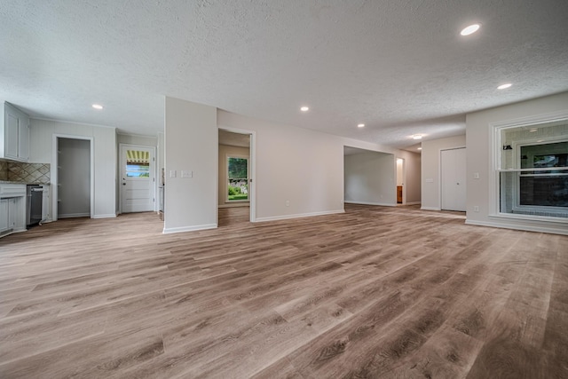 205 Walnut St, Smyrna, TN 37167 - unfurnished living room with a textured ceiling, a fireplace, light wood-style floors, and recessed lighting