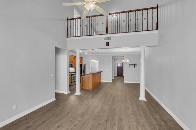 2342 N Tennessee Blvd Unit 603, Murfreesboro, TN 37130 - unfurnished living room featuring ornate columns, ceiling fan, light wood-style flooring, a towering ceiling, and a chandelier