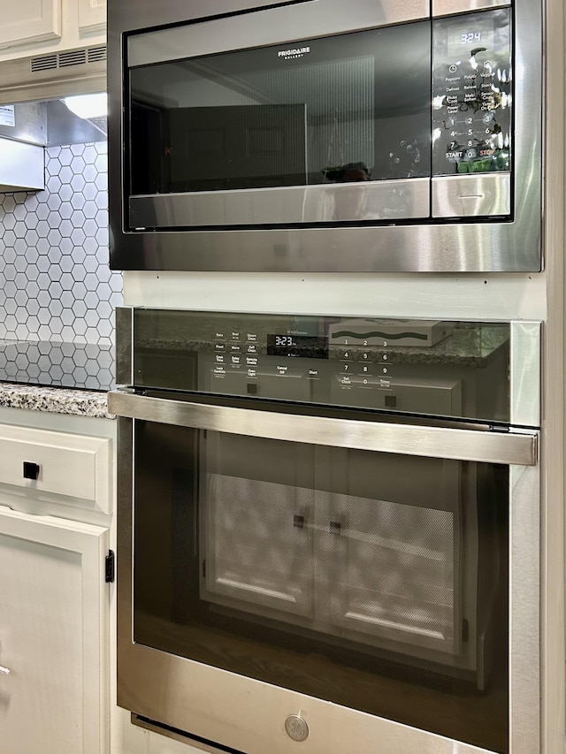 1307 Tomahawk Trce, Murfreesboro, TN 37129 - kitchen view of stainless steel oven, extractor fan, tasteful backsplash, and white cabinetry