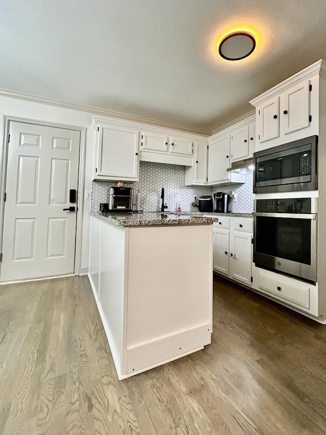 1307 Tomahawk Trce, Murfreesboro, TN 37129 - kitchen featuring appliances with stainless steel finishes, white cabinetry, wood finished floors, a peninsula, and backsplash