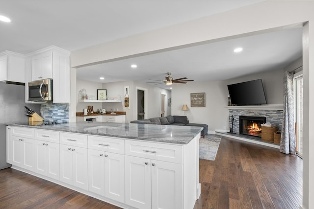 2913 New Hope Rd, Hendersonville, TN 37075 - kitchen with stainless steel microwave, a peninsula, white cabinetry, light stone countertops, and a fireplace