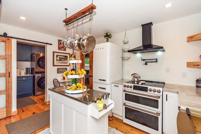 145 W Hollis Chapel Rd, Portland, TN 37148 - kitchen featuring wall chimney exhaust hood, stacked washer / dryer, double oven range, light wood-type flooring, and recessed lighting