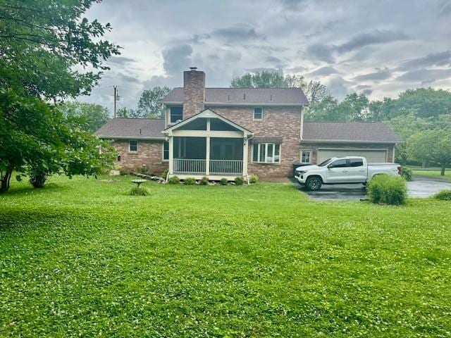303 Revere Ln, Franklin, TN 37064 - rear view of property featuring a chimney, brick siding, an attached garage, a lawn, and a sunroom