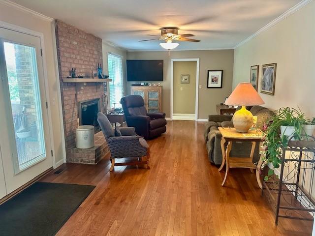 303 Revere Ln, Franklin, TN 37064 - living room with a brick fireplace, wood finished floors, a ceiling fan, and ornamental molding