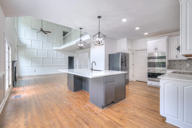 1202 Willow Brook Pass, Mount Juliet, TN 37122 - kitchen featuring stainless steel appliances, light countertops, backsplash, a kitchen island with sink, and light wood-style floors
