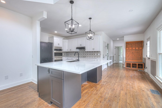 1202 Willow Brook Pass, Mount Juliet, TN 37122 - kitchen featuring a chandelier, backsplash, light wood-type flooring, white cabinets, and light countertops