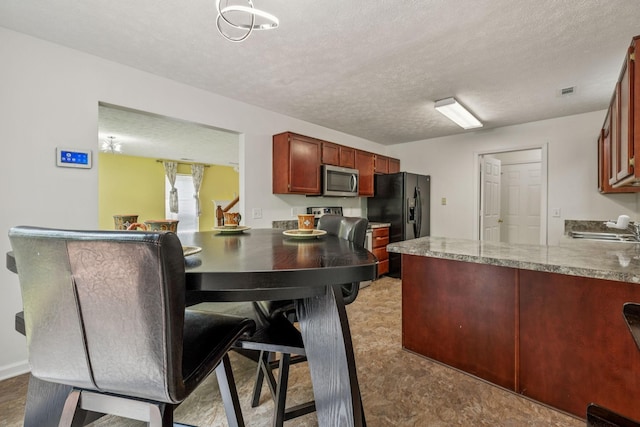 3524 Glenfalls Dr, Hermitage, TN 37076 - kitchen with stainless steel microwave, black fridge, a peninsula, reddish brown cabinets, and a textured ceiling
