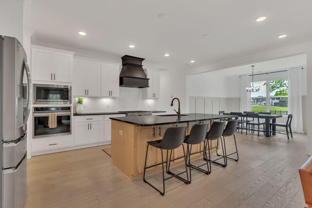 5509 Bridgemore Blvd, Murfreesboro, TN 37129 - kitchen with stainless steel appliances, custom range hood, light wood-type flooring, a kitchen bar, and a chandelier