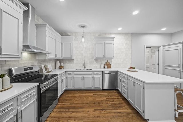 1183 Buckingham Cir, Franklin, TN 37064 - kitchen featuring appliances with stainless steel finishes, wall chimney exhaust hood, a peninsula, light countertops, and decorative backsplash