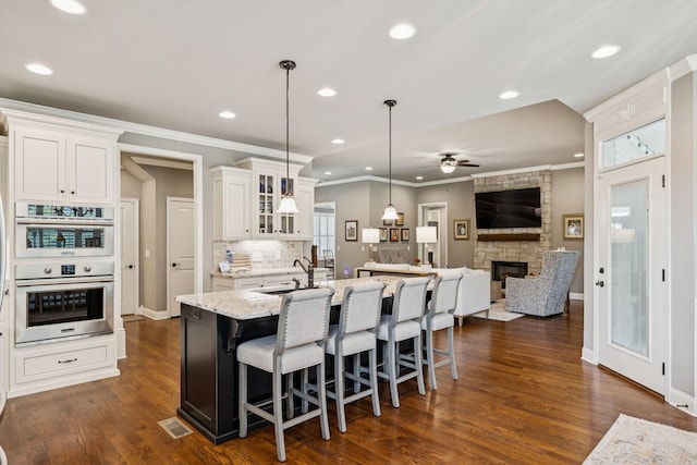 1120 Pretender Way, Columbia, TN 38401 - kitchen with light stone countertops, white cabinets, glass insert cabinets, ceiling fan, and ornamental molding