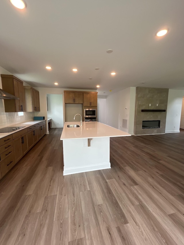 1559 Oak Springs Dr, Columbia, TN 38401 - kitchen with stainless steel microwave, a center island with sink, wood finished floors, light countertops, and backsplash
