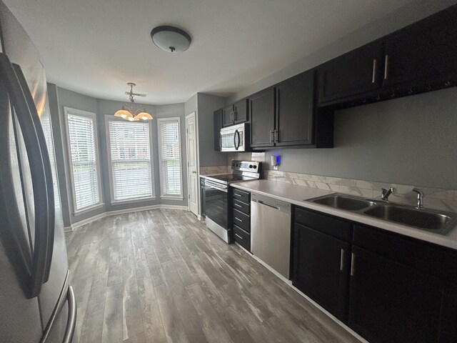 7206 Rosemary Ct, Fairview, TN 37062 - kitchen featuring appliances with stainless steel finishes, dark cabinets, a chandelier, and light wood-type flooring