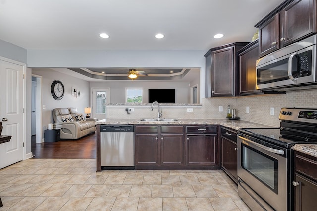 4611 Turquoise Ln, Murfreesboro, TN 37129 - kitchen featuring stainless steel appliances, open floor plan, a tray ceiling, dark brown cabinets, and recessed lighting