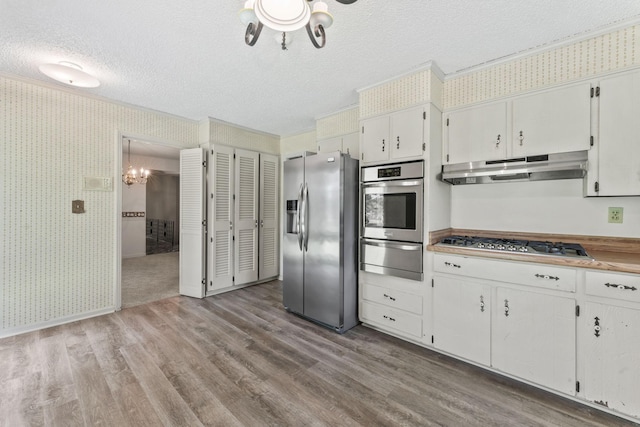 123 Proffitt St, Carthage, TN 37030 - kitchen featuring appliances with stainless steel finishes, a warming drawer, under cabinet range hood, a textured ceiling, and wallpapered walls