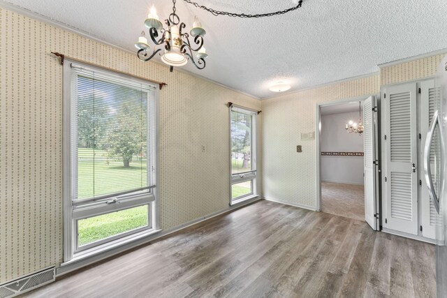 123 Proffitt St, Carthage, TN 37030 - unfurnished dining area with a chandelier, ornamental molding, a textured ceiling, wallpapered walls, and wood finished floors