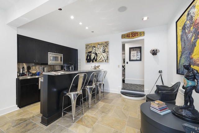 2410 Hidden River Ln, Franklin, TN 37069 - kitchen featuring dark cabinets, stainless steel microwave, a breakfast bar, stainless steel countertops, and recessed lighting