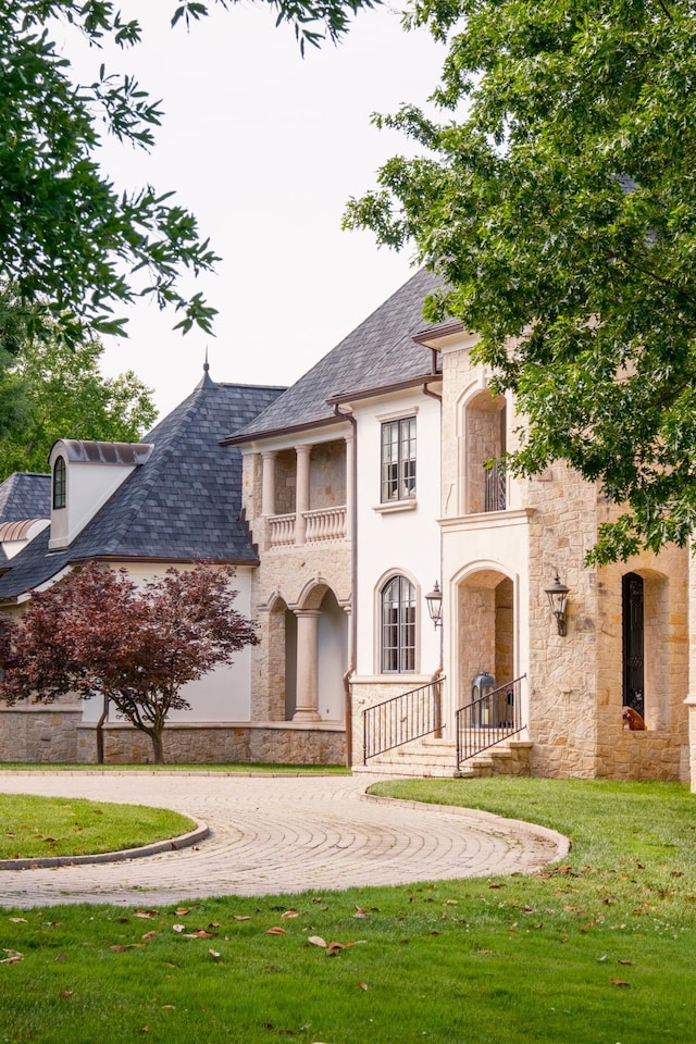 2410 Hidden River Ln, Franklin, TN 37069 - french country inspired facade with a balcony, stone siding, a front yard, curved driveway, and stucco siding