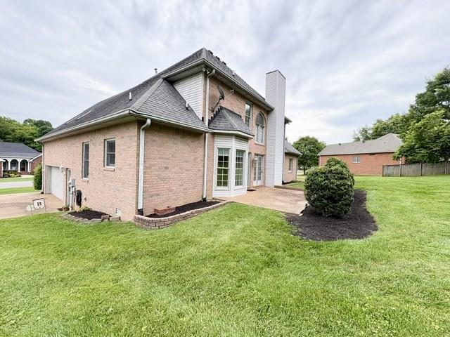 416 Barnes Dr, Lebanon, TN 37087 - rear view of house featuring brick siding, a chimney, a garage, and a shingled roof