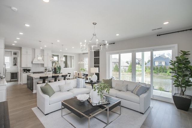 5969 Hunt Valley Dr, Spring Hill, TN 37174 - living room featuring a chandelier, beverage cooler, recessed lighting, plenty of natural light, and light wood finished floors