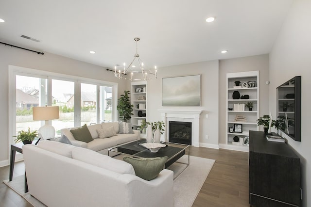 5969 Hunt Valley Dr, Spring Hill, TN 37174 - living room featuring built in features, dark wood-style floors, a chandelier, recessed lighting, and a glass covered fireplace